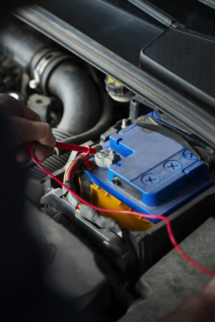 Close-up of a mechanic checking car battery voltage with a multimeter at a Sugar Land auto repair shop