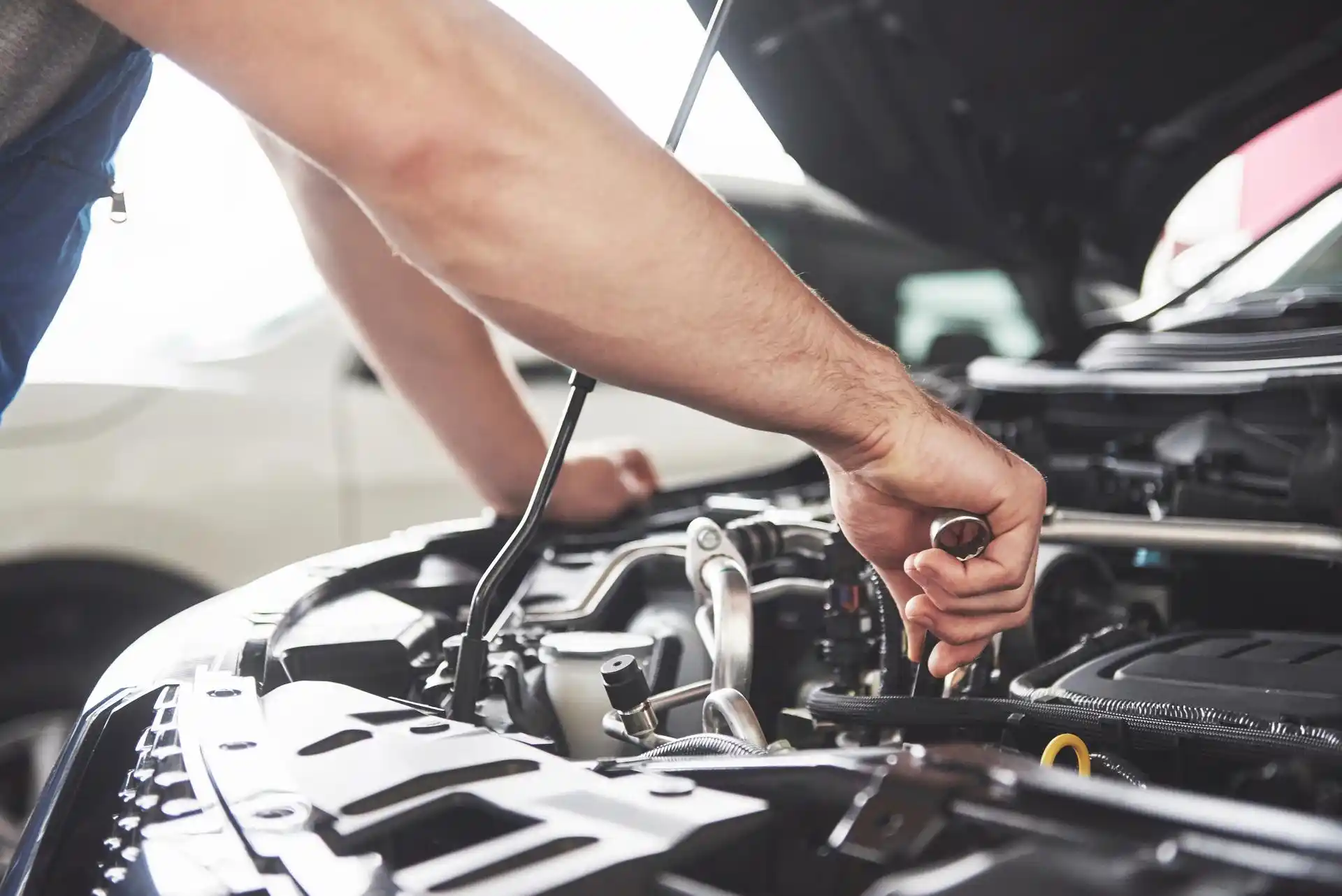 Close-up of a mechanic performing engine maintenance and service on a car at a Sugar Land repair shop.
