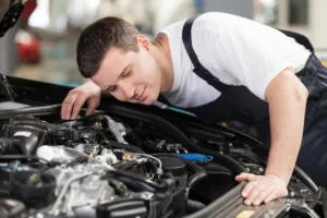 A concerned mechanic in a garage, leaning over a car's engine bay with a serious expression, listening for unusual noises.