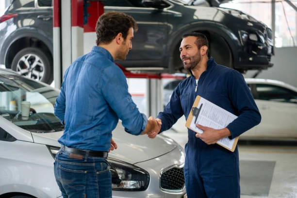 A friendly mechanic shaking hands with a satisfied customer in a professional auto repair shop, showing trust and reliability in Sugar Land.