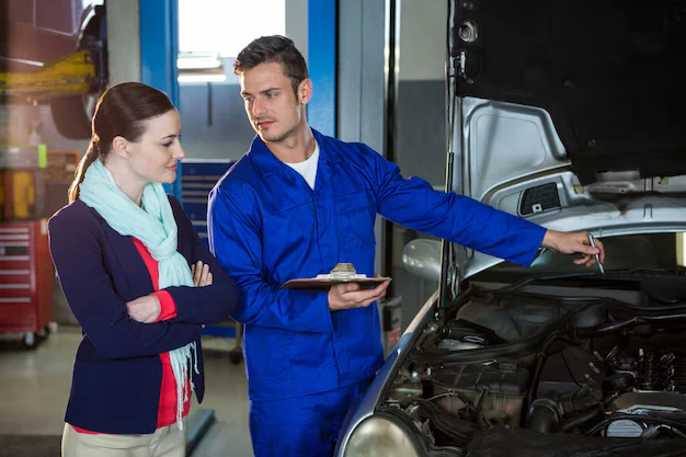 A mechanic showing a customer a transparent digital repair quote on a tablet at a Sugar Land auto shop.
