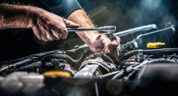A skilled mechanic in a professional auto repair shop performing general car repair and engine diagnostics.