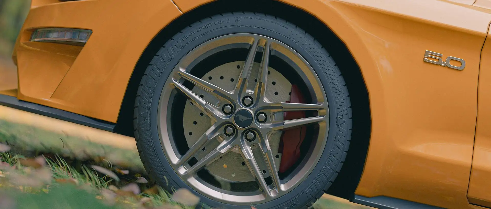 A close-up view of a car's tire, wheel, and brake rotor, highlighting the wheel's design and the tire's tread.